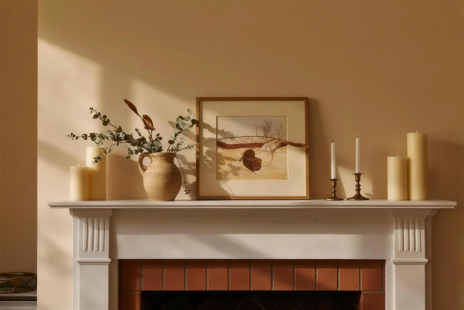 Narrow painted mantel styled with a stoneware pitcher of eucalyptus, pillar candles and a leaning framed print